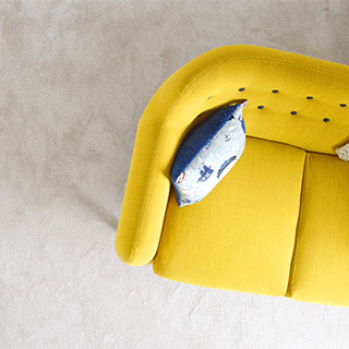 Top down photo of minimal yellow couch with stylish blue pillow