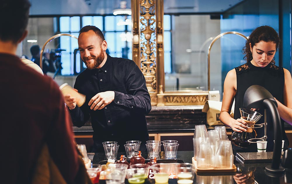 Photo of bartenders behind bar serving drinks