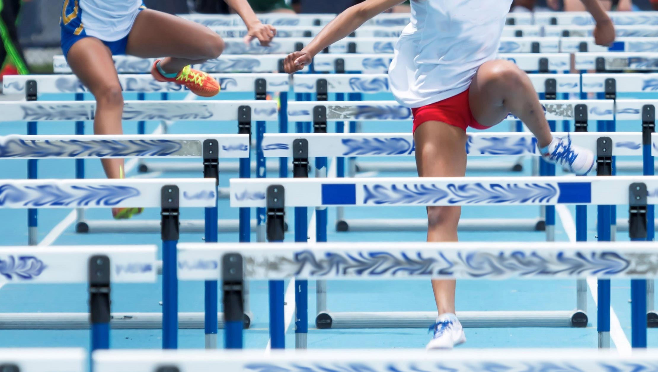 Photo of 2 people competing in hurdles track event